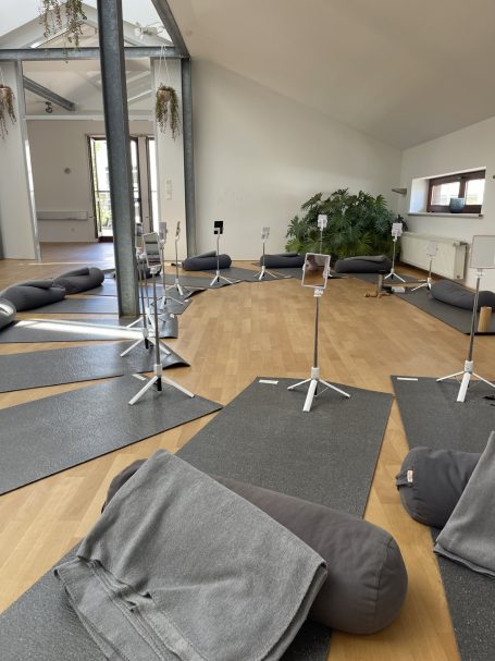 Face Yoga im Tribe Yoga Base Ottensen Ein Raum mit Yogamatten, Bolstern, Decken und Spiegeln auf Stativen im Halbkreis angeordnet